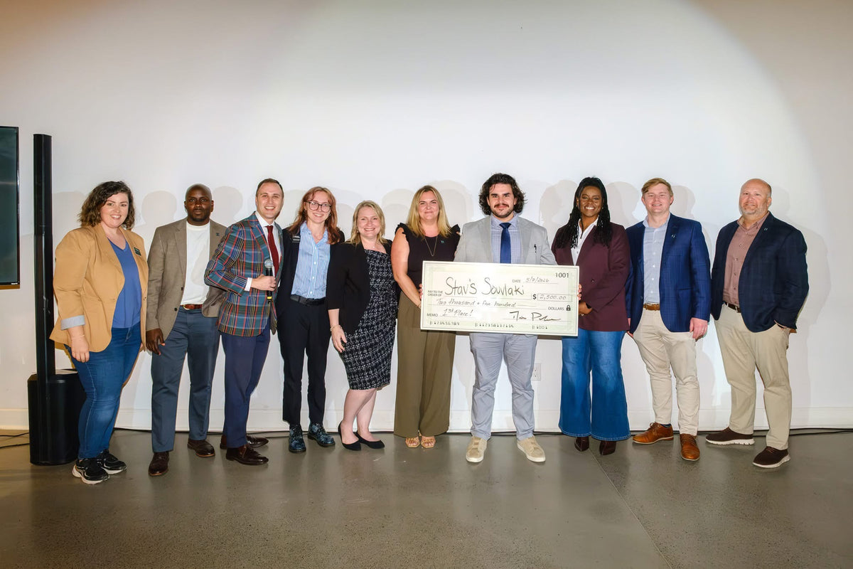 Stavros holding the first-place prize at the GRIT Pitch competition